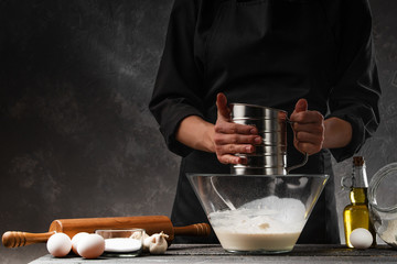 A professional chef cooks dough and works with flour. Bakery background, recipe book, restaurant business and hotel business