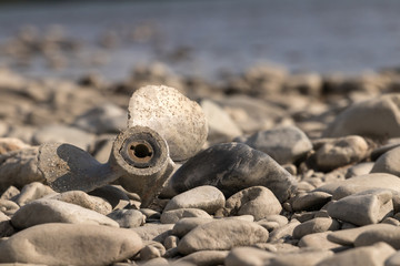 Broken motor for a boat lies on a rocky riverside