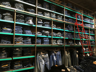 Piles of modern jeans of different sizes. A wide selection of jeans in a clothing store. Shelves with clothes in the department of cotton products.
