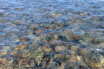Ripples in shallow water - clear cold water and colored stones at the bottom