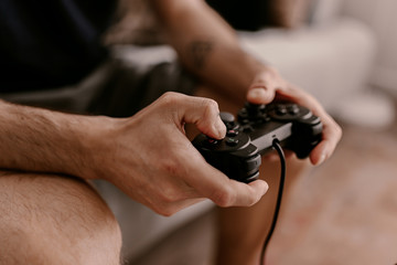 Hipster man plays video games on a couch. Relaxing time. Fun weekend. Concentrated on a video game. Winning the game, gambling. Multiplayer game. Online gaming. Streaming video game. Soccer, racing © Regina Foster