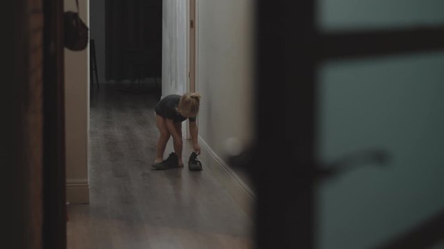 Three year old toddler girl want to try on all the shoes they have at home. Begininning with brother boots