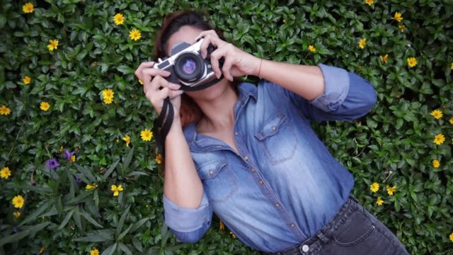 Latin woman with camera lying down in flower field