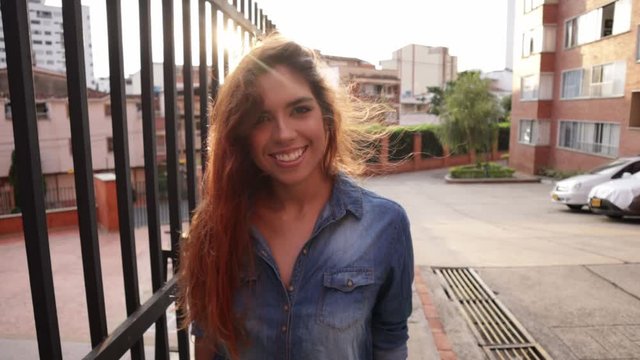 Latin woman moving hair and smiling with sunset behind