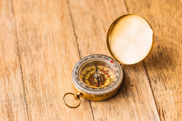 One single brass compass on top of a wooden table