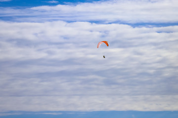 Paraglider flies high in the sky in beautiful clouds