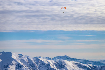 Paraglider flies high above the Caucasus mountains in the clouds