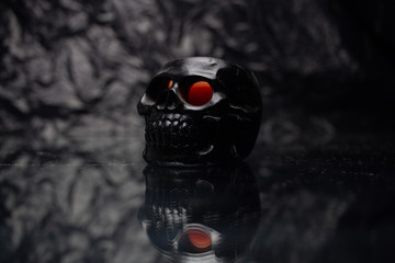 candle in the form of a skull on a black background with a reflection at the bottom