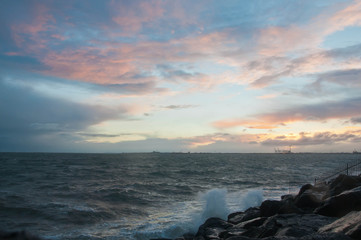 Dramatic splashing ocean wave in the evening with twilight sky in Winter at breakwater at St Kilda pier in Melbourne Australia