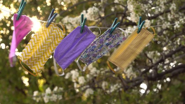 A reusable DIY fabric cotton mask is dried on a clothesline in the open air for reuse. Cloth Face Mask Washing, Drying, Cleaning, Disinfection and Sterilization. Covid-19 Pandemic