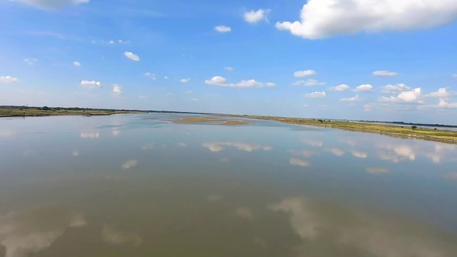 clear blue sky with many small cloud patch and river water reflection