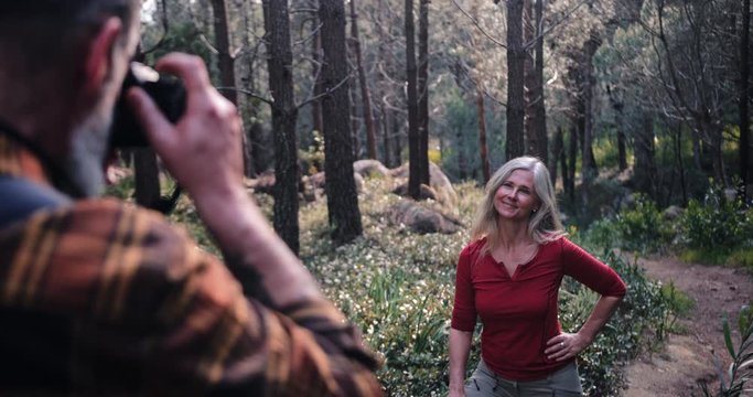 Senior man taking picture of senior woman on forest