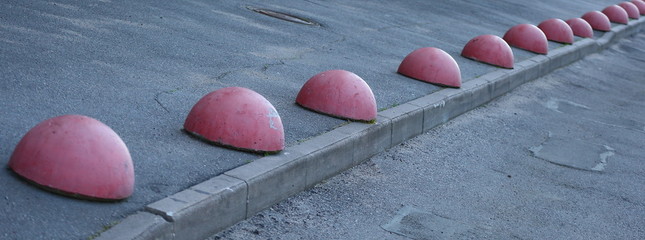 Barrier of a number of red concrete half-spheres on the sidewalk