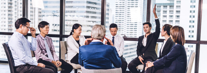 Businessman standing in front of group of people in consulting meeting conference seminar and showing hand to answer question at hall or seminar room.presentation and coaching concept