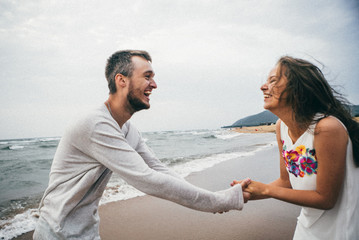 
Happy lovers have a cheerful vibes on sea beach at sunset 
