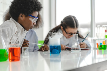 Group of teenage cute little students child learning research and doing a chemical experiment while making analyzing and mixing liquid in test tube at experiment laboratory class at school.Education