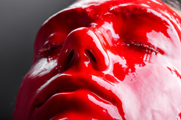 Image of a young female's face with glossy red paint