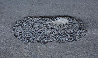 Rubble-covered pothole in the road surface