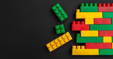 Multicolor toy bricks on black background. Space for text.