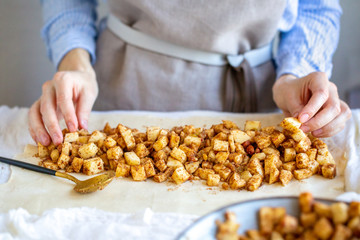 Cooking apple strudel. Girl is preparing a pie at home in an apron. Work with puff pastry. The process of making apple strudel. Rash fillings in puff pastry. Sliced ​​apples are placed in the dough.