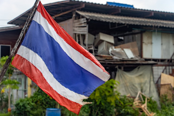 The national flag of Thailand flutters on the street on the outskirts of the city.