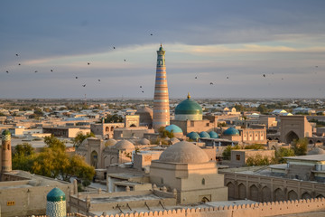 Beautiful cityscape with large islamic minaret over Khiva, Uzbekistan, seen from air during sunset,...