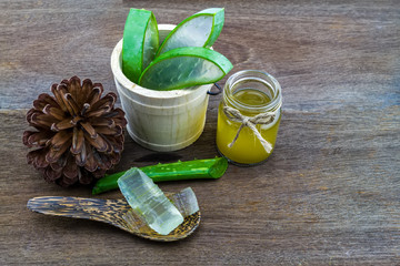 Fresh aloe vera gel on wooden  spoon with aloe  vera essential oil and pine   on wooden table