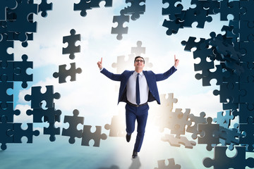 Businessman breaking the wall of jigsaw puzzle