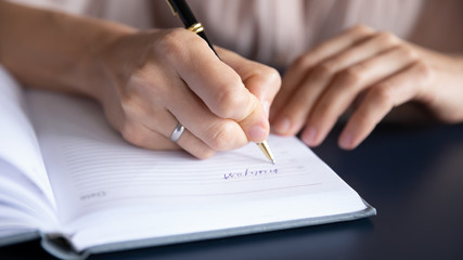 Close up female hand holding pen, writing information in notebook, young female businesswoman planning day, making notes, handwriting, student preparing for exam, studying at home