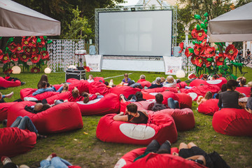 people at city public park watching movie at open air cinema