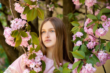 Fototapeta premium Portrait of a beautiful teenage girl in delicate sakura flowers