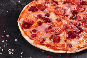Pepperoni pizza with mozzarella cheese, salami, tomatoes, pepper and spices
