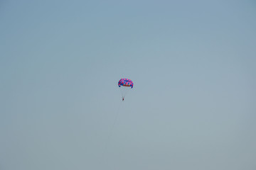 Ocean view of a man parasailing in the sea, towed by speedboat, nature activity outdoors, summer, parasail above water