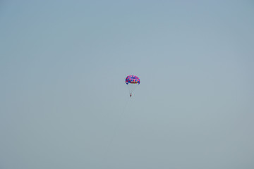 Ocean view of a man parasailing in the sea, towed by speedboat, nature activity outdoors, summer, parasail above water