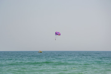 Ocean view of a man parasailing in the sea, towed by speedboat, nature activity outdoors, summer, parasail above water