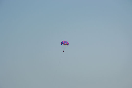 Ocean view of a man parasailing in the sea, towed by speedboat, nature activity outdoors, summer, parasail above water