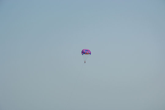 Ocean view of a man parasailing in the sea, towed by speedboat, nature activity outdoors, summer, parasail above water