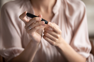 Obraz na płótnie Canvas Close up young woman measuring glucose level, blood sugar ranges, using lancet pen on finger, unhealthy female using blood glucose meter, diabetes, healthcare and insurance concept