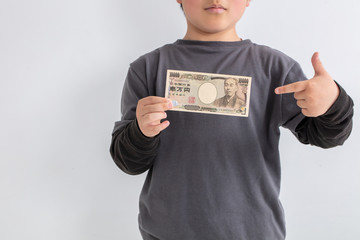 男の子が一万円を持って指を指している　児童手当　給付金　日本　money ...