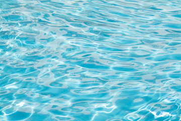 Fototapeta na wymiar Water surface background. Blue pool water with sun reflections. Ripples of water in the pool.