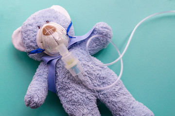 Medicine layout or flat lay. Children's toy masked by inhaler. The blue bear symbolizes the child...