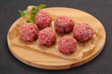 Raw meatball over wooden background