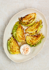 Baked cabbage slices. Healthy grilled vegetable steaks with sauce and seasonings in a white plate. useful food. Vegan, vegetarian diet. Selective focus, top view