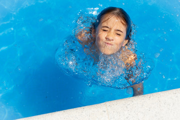 Cute girl eight years old playing in a swimming pool.