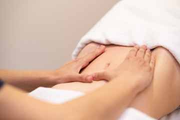 Obraz na płótnie Canvas Woman receiving a belly massage at spa salon
