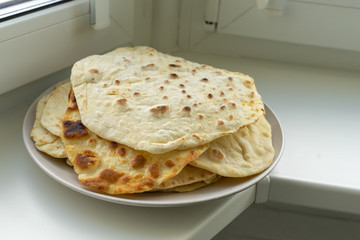 a plate of fried tortillas stands on a windowsill.