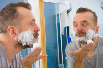 Guy shaving his beard in bathroom