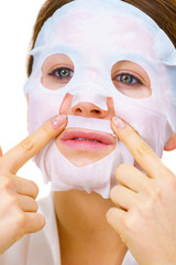 Woman applying sheet mask on face