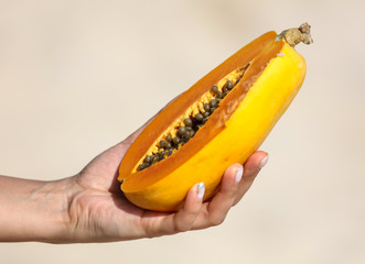 Papaya cut with a knife in the hands.