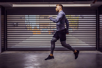 Fototapeta premium Young attractive muscular sportsman running in underground garage.